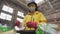 Woman-volunteer in yellow jacket and transparent protecting glasses, hard hat and mask sorting used plastic bottles at