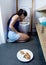 Woman vomiting and throwing up kneeling on floor of toilet WC guilty after eating pizza