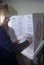 Woman voter in a voting booth selecting choices on a ballot, CA