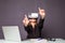 Woman in VR glasses. Confident young woman in virtual reality headset pointing in the air while sitting at her working place in of