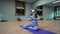 Woman in VR glasses sits in Lotus pose on blue mat in studio