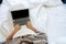 Woman waer robe wrap with blanket using laptop on her bed