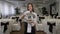 A woman waiter holds a tray with a covered dish in a restaurant.