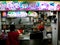 A woman waits for her order at the restaurant of a typical Singapore food court or Hawker