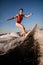 Woman wakesurfer in red swimsuit rides up the wave on surfboard