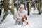 A woman on a walk with her dog in the winter forest. mistress and dog game in the snowy forest