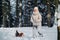 A woman on a walk with her dog in the winter forest. mistress and dog game in the snowy forest