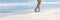 Woman walk on sea beach. Summer vacation, holidays, travel. Female barefoot feet walking ocean shore. Banner, copy space