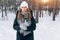 Woman on a walk in the winter forest drinking tea from a thermos