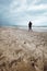 Woman walking alone on the beach on windy stormy day