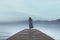 woman walking alone on a pier by the sea in a surreal atmosphere in the blue hour