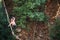 A woman is walking along a stretched sling over a forest