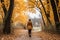 Woman walking on autumn forest path surrounded by vibrant foliage in woods background