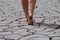 Woman walking barefoot across cracked earth