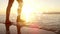 Woman walking barefoot in ocean on the sand against sunshine on ocean