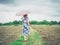 Woman walking in barren field with umbrella