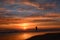 Woman walking on the beach at sunrise.