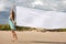 Woman walking on the beach with a white tissue