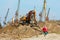 Woman walking on concrete slab towards excavator