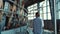 Woman walking cows milking parlour rear view. Modern dairy production facility.