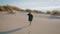 Woman walking desert dunes in black dress. Girl stepping sand making footmarks.