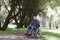 Woman walking with disabled man in wheelchair in park