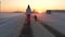 Woman Walking With A Dog In The Snowy Winter On The Road At Sunset