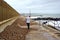 Woman walking dogs. Sea wall storm damage