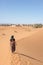 Woman walking in the dunes in the Moroccan Sahara desert