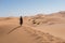 Woman walking in the dunes in the Moroccan Sahara desert