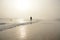 Woman walking on the foggy beach.