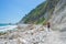 Woman walking on italian beach. Uneven Conero coast line, pebble beach, turquoise water real people, rear view, sunny day,