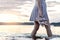 Woman walking in lake water in Finland on an evening at sunset or summer night. Lady holding shoes in hand. Dramatic mood.