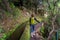 Woman walking on levada 25 fountains in Rabacal, Madeira island.