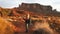 Woman walking in Monument Valley taking photos with smartphone.
