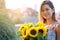 Woman is walking in the old town. He is holding a bouquet of autumn sunflowers in his hand