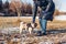 Woman walking pug dog in snowy winter park by frozen lake holding leash. Puppy wearing harness