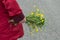 woman walking on the road with red coat taking a wild bouquet flowers in hand