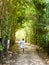 Woman walking in rustic pathway between trees on a sunny day
