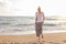 Woman walking on sand beach at golden hour