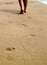 Woman walking on sand beach leaving footprints