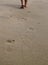 Woman walking on sand beach leaving footprints