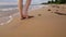 Woman walking on sand beach leaving footprints in the sand