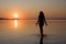 Woman walking in sea at sunset