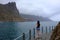 Woman walking on the seafront with mountains and cloudy sky on background