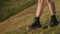woman is walking on slope of hill at summer day, closeup of feet