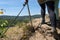 A woman walking a trail through the vineyards on a rocky, slate surface in specialized climbing shoes by a metal railing, in the b