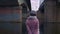 Woman walking by water under bridges. Stock footage. Rear view of attractive young woman walking under old bridges in