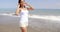 Woman Walking on Windy Beach with Hands in Hair