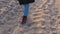 Woman walking on winter beach. Feet in red boots at Cold Autumn Day. Girl steps